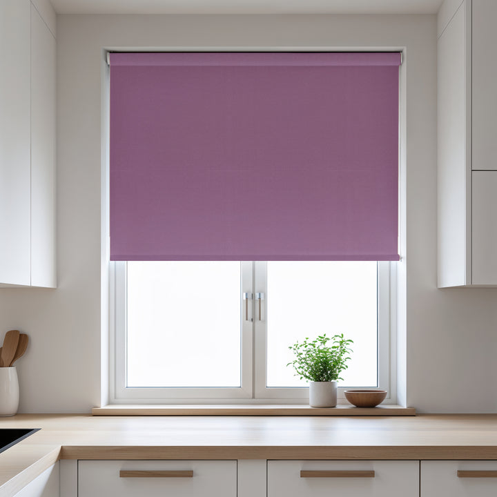 Purple roller blind on a window in a kitchen with white cabinets and a wooden countertop.