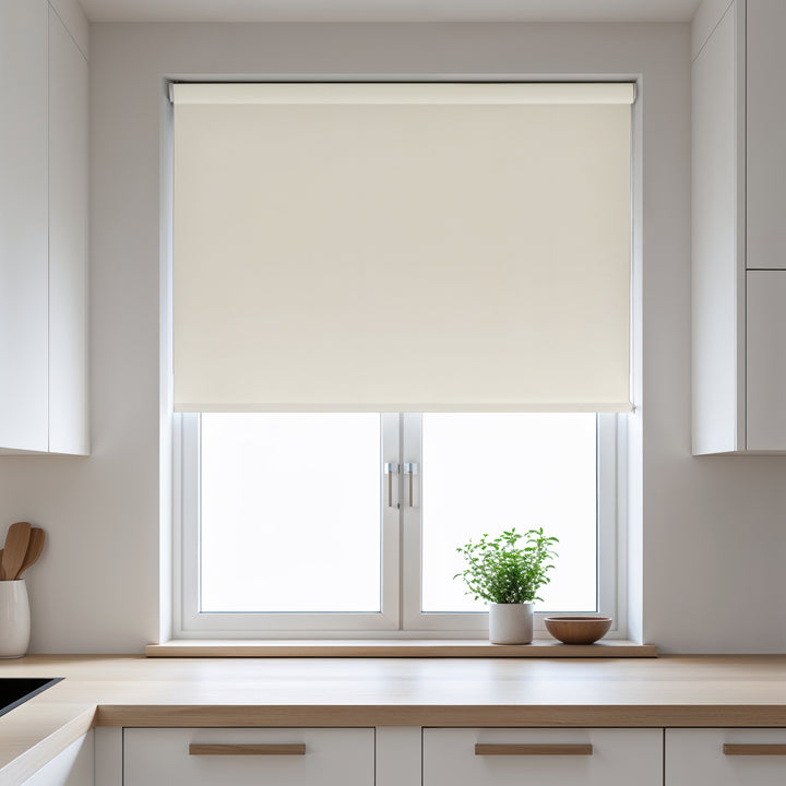 Beige roller blind on a window in a kitchen with light-colored walls and wooden countertops.