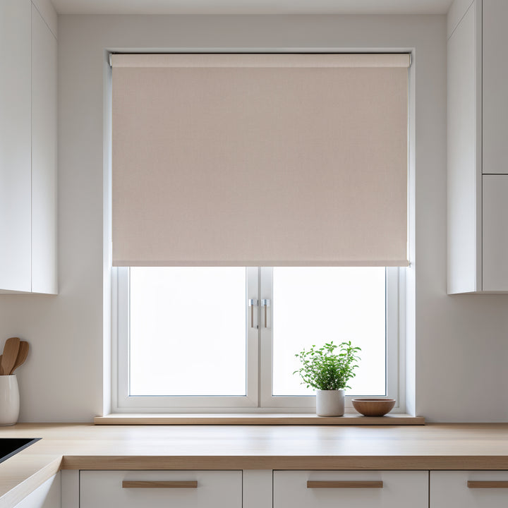 Beige roller blind on a window in a kitchen with light-colored walls and wooden countertops.